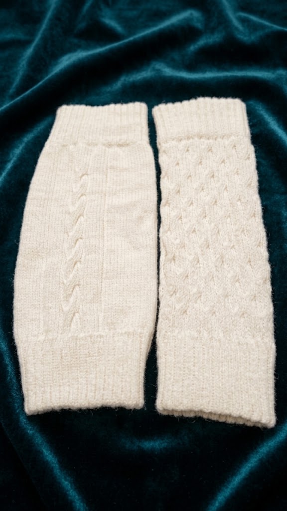 Par de polainas em tricô off-white com padronagem de tranças e canelados.